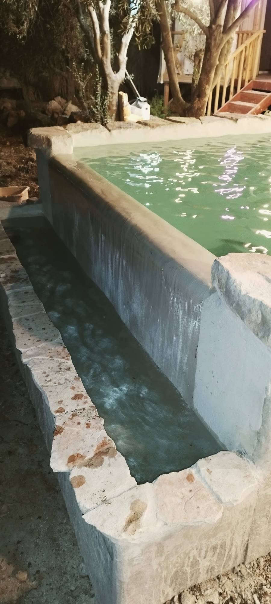 המים גולשים משפת הבריכה בלילה